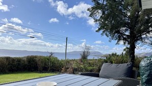 A table with a floral mug, wicker furniture, and a view of the sea and mountains. -  Lakeside Lough Mask shore (Tourmakeady)