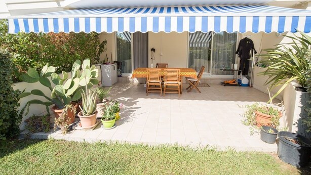 A patio with a table and chairs, surrounded by potted plants and a striped awning. - Comfortable apartment near the beach and services (Saint-Raphaël)