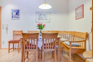 A dining area with wooden chairs and a table, a bench, and wall-mounted pictures.