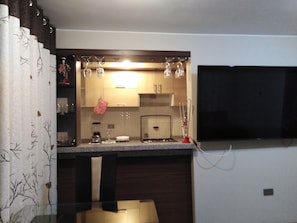 A compact kitchen with a built-in microwave, a gas stove, and a hanging pot rack. - Duplex 2 rooms (San Martín de Porres)