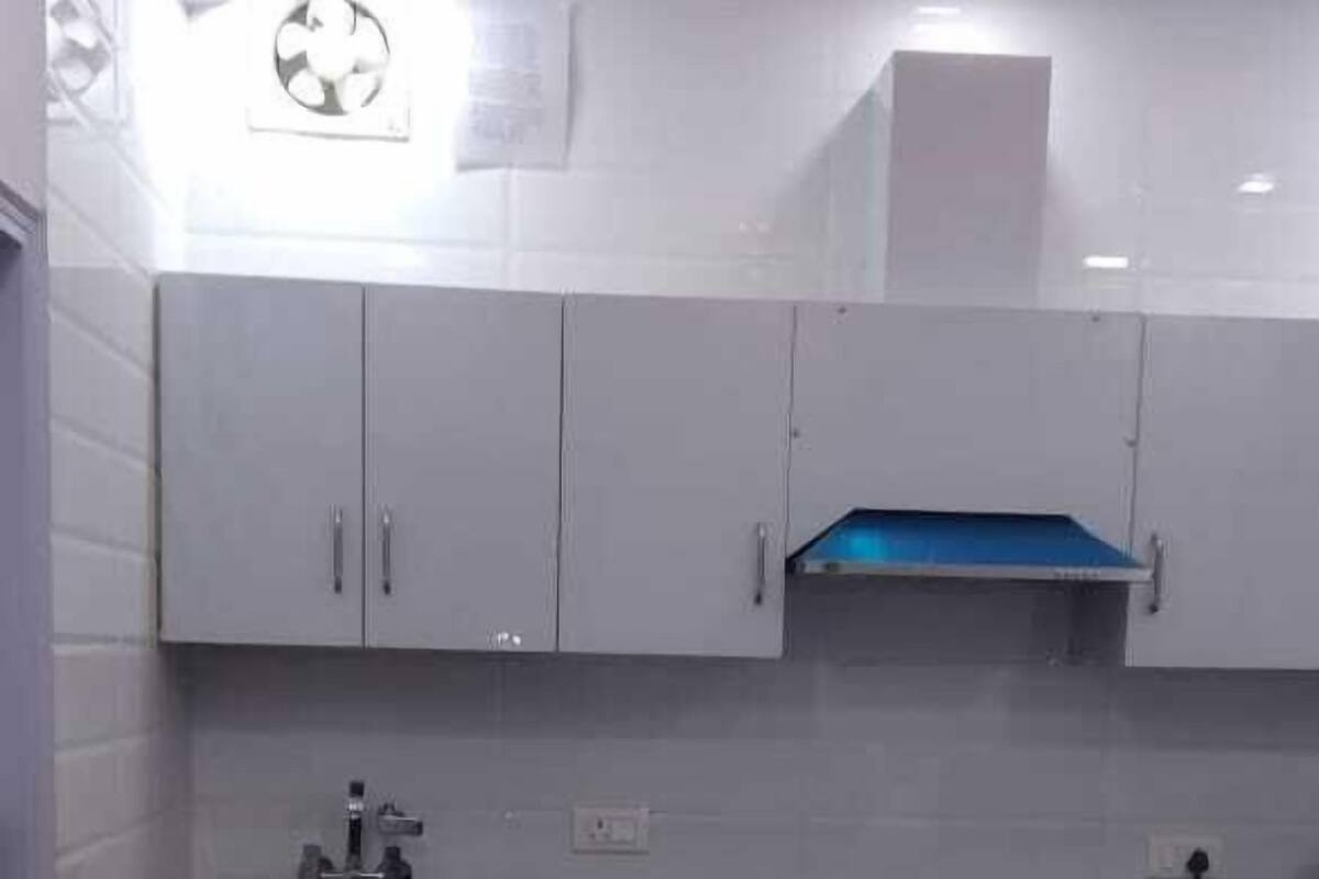 A compact kitchen with white cabinets, a blue range hood, and a sink.