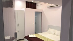 A bedroom with a bed, a wardrobe, and an air conditioning unit. - Atul's Europa Apartments (New Delhi)