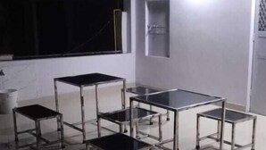 A rooftop terrace with a table and chairs, a white wall, and a window. - Atul's Europa Apartments (New Delhi)