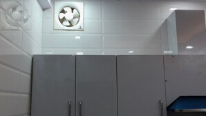A kitchen with white cabinets, a ceiling fan, and a recessed light. - Atul's Europa Apartments (New Delhi)