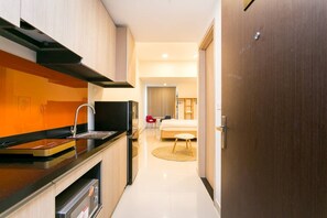 Enjoy a compact kitchenette with a stove, sink, and dishwasher, complemented by a wooden countertop and black backsplash.