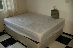 A single bed with a white mattress in a room with black and white checkered flooring. - GATED COMMUNITY, 24-HOUR SECURITY, SWIMMING POOL WITH HYDROMASSAGE.  (Peruíbe - SP)