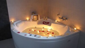 A bathtub with rose petals and candles, suggesting a romantic setting. - Studio with Jacuzzi "Balcony of the Len" (Soba)