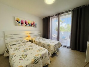 Une chambre d’hôtel avec deux lits, un tableau au mur, une fenêtre avec des rideaux et une vue sur l’extérieur.
