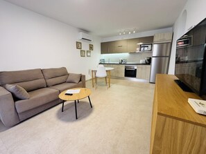 Eine moderne Wohnung mit Wohnzimmer, einer kleinen Essecke und einer Küche.