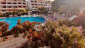 Un hôtel doté d’une piscine entourée de chaises longues et de plantes en pot.