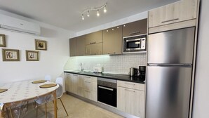 A modern kitchen with a stainless steel refrigerator, microwave, and dishwasher. There is a dining table with chairs and framed pictures on the wall. - Americas Holiday Home (Playa de las Américas)