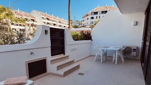 A balcony with a table and chairs, a sofa, and a small staircase. - Americas Holiday Home (Playa de las Américas)