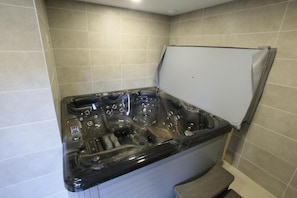 A corner bathroom with a black bathtub, tiled walls, and a white shower enclosure.