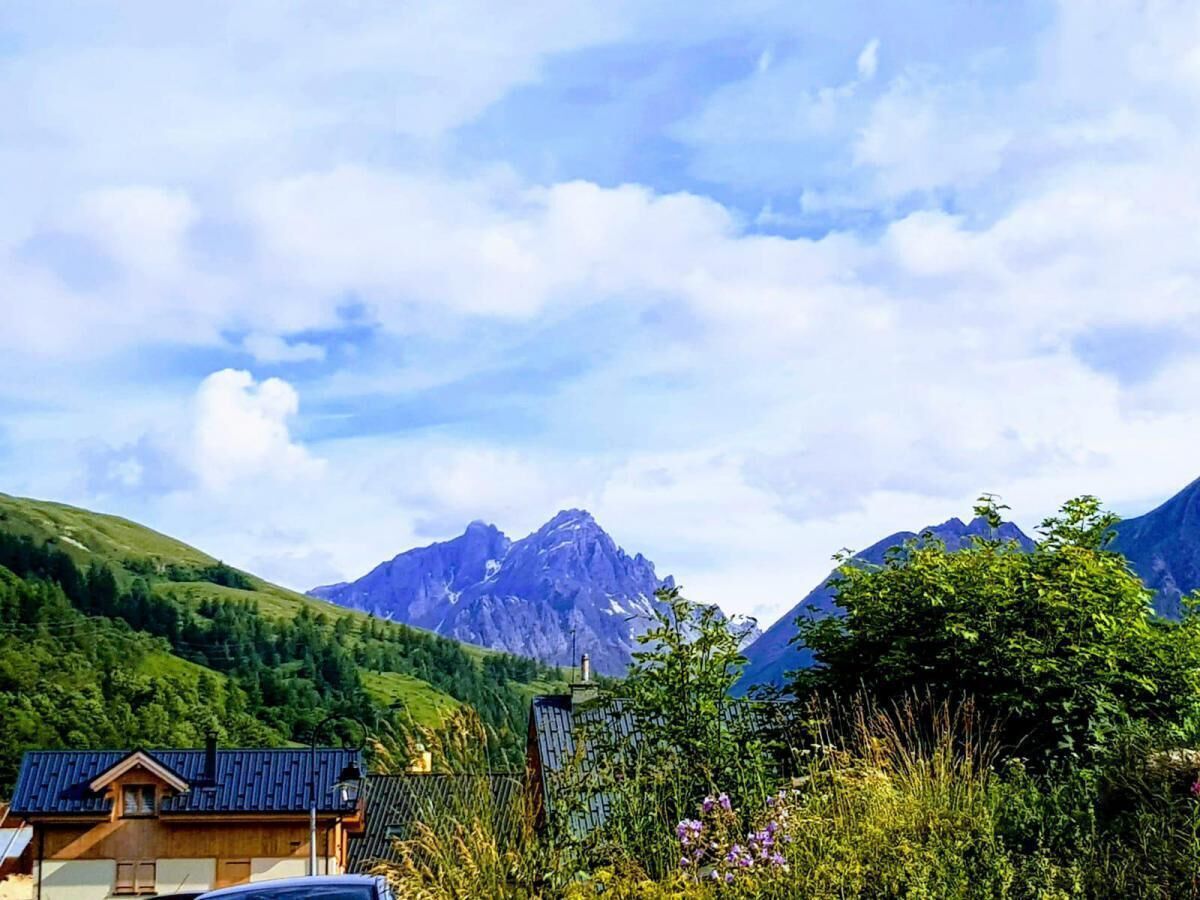 A mountain landscape with a house in the foreground.