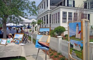 Artistic display on the sidewalk, featuring local paintings and a historic building in the background.