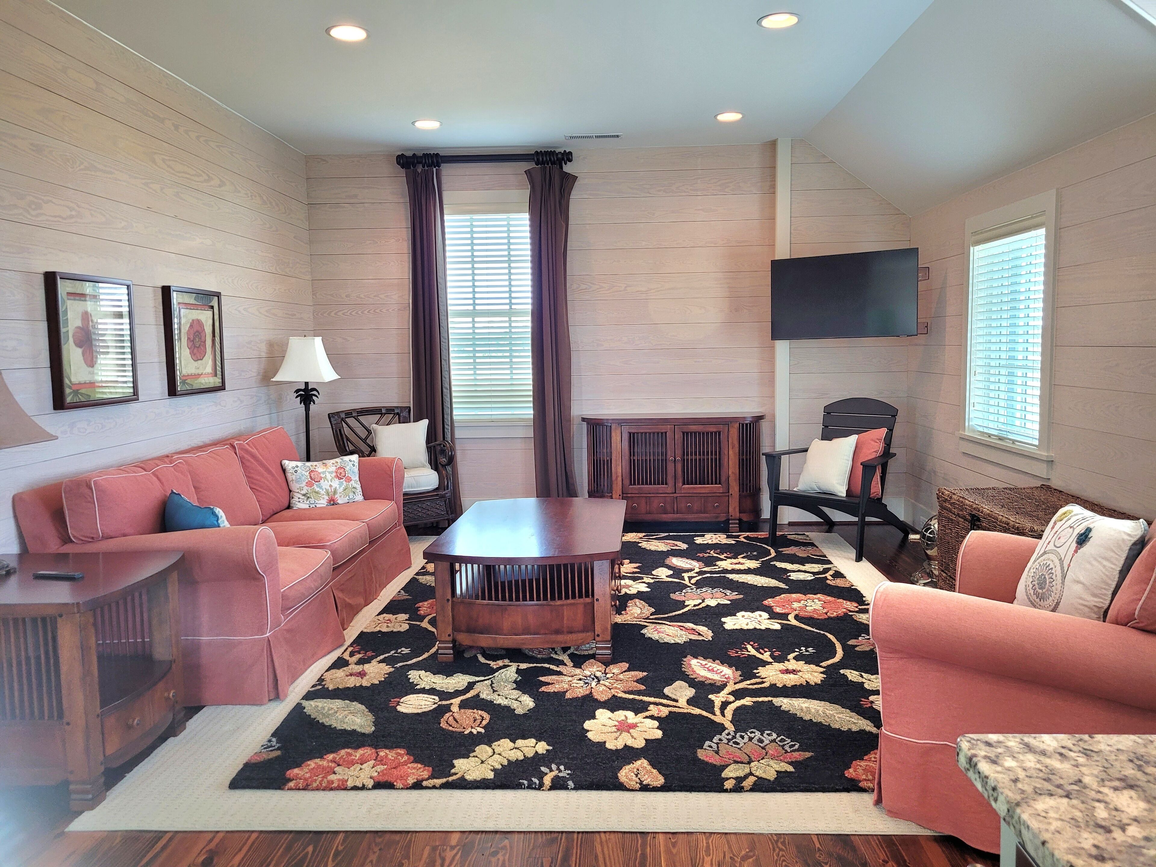 A living room with a sofa set, a coffee table, a cabinet, and a TV mounted on the wall.
