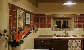 Enjoy cooking in this well-equipped kitchen with a sink, wooden countertop, and a potted plant.
