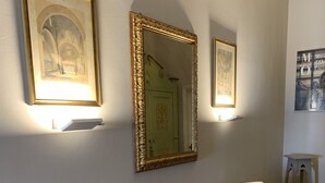 Uma sala de jantar com uma mesa redonda de madeira, duas cadeiras brancas estofadas e três luminárias fixadas na parede.