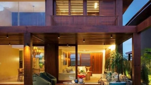 Ein modernes, zweigeschossiges Haus mit einer Holzterrasse und einem Swimmingpool.