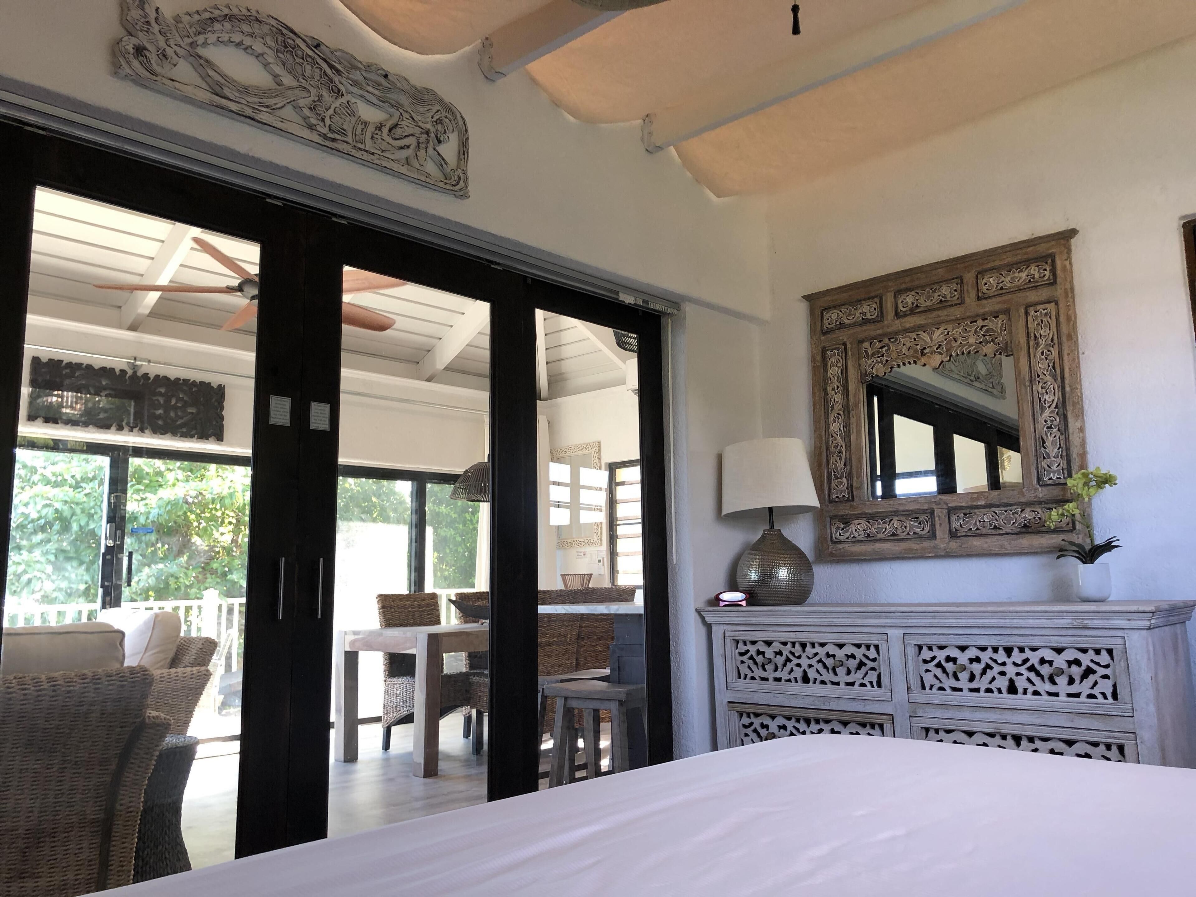 A room with a bed, a large mirror, and a view of the outside.