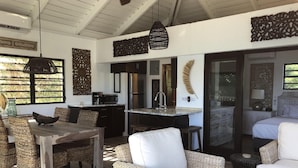 A modern interior with a dining area, kitchen, and a bedroom.
