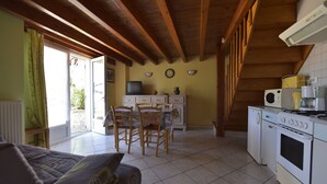 Una cocina acogedora con vigas de madera, un comedor con sillas, un televisor y una estufa.
