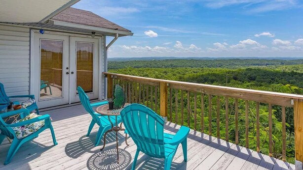A deck with turquoise chairs and a table, overlooking a forested landscape. - Viewtopia - New Hot Tub with Amazing Views on 160+ acres (Rock Spring)