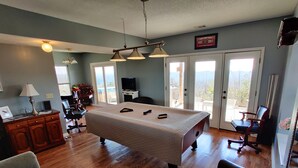 A spacious room with a pool table, a sofa, and a chair. There is a TV and a cabinet with a lamp. - Viewtopia - New Hot Tub with Amazing Views on 160+ acres (Rock Spring)