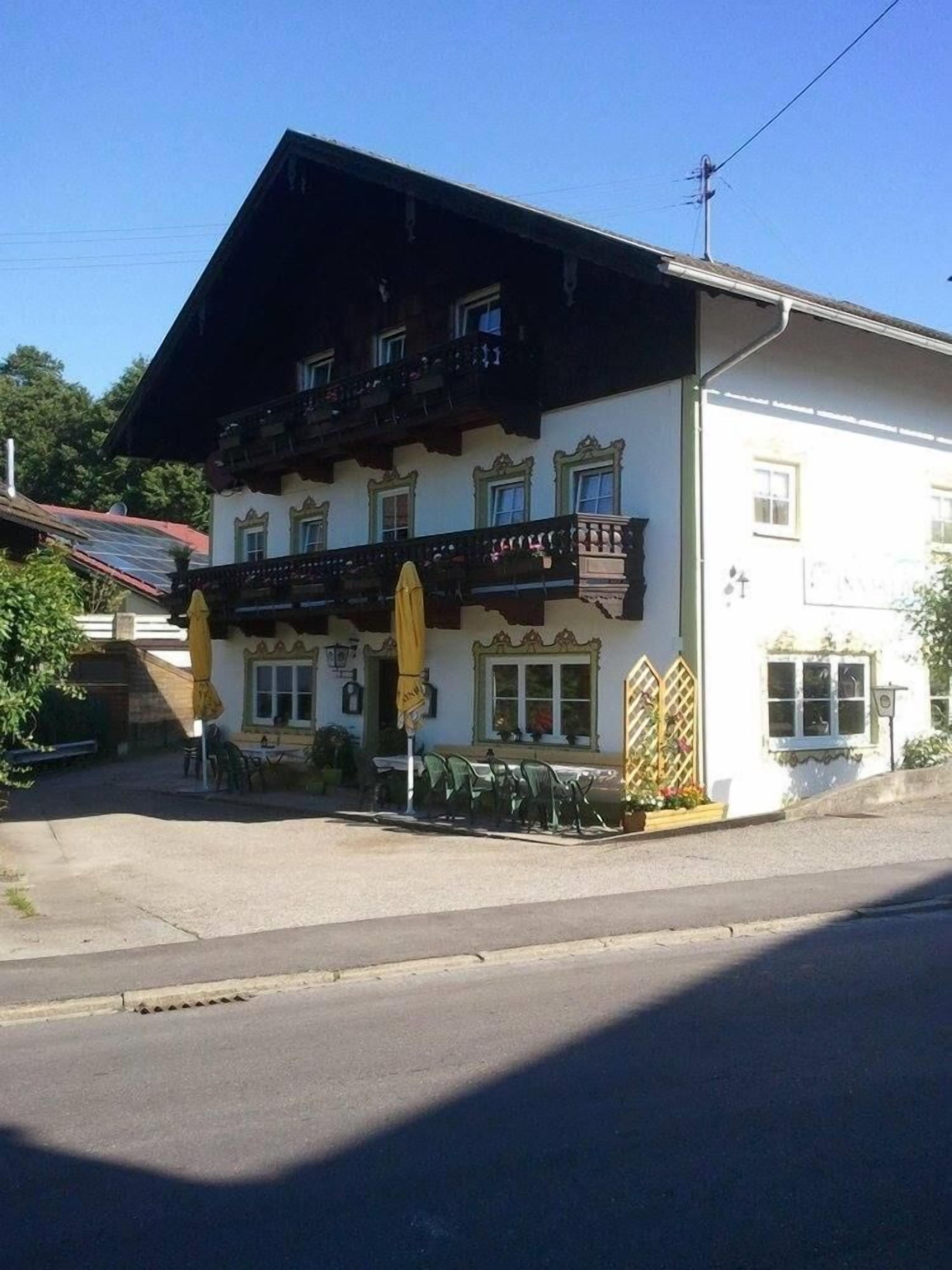 A two-story building with a balcony, outdoor seating, and a sign indicating a restaurant or cafe.