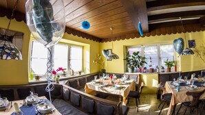 A dining area with a wooden ceiling, large windows, and a table set for a meal. - Inntalhof Pension (Raubling)