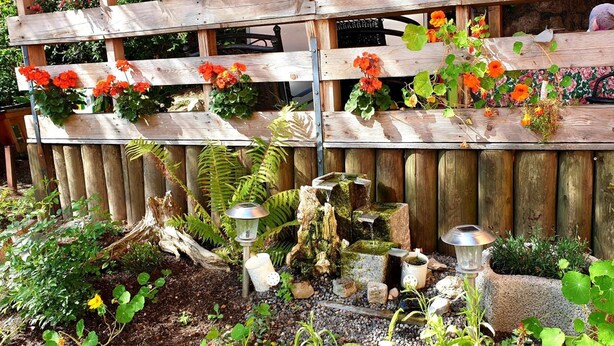 A wooden garden with a wooden fence, various plants, and decorative garden lights. - Inntalhof Pension (Raubling)