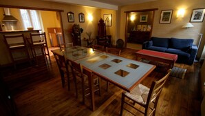 Een eethoek met een tafel met glazen blad en houten stoelen, een bank en een klein bijzettafeltje.