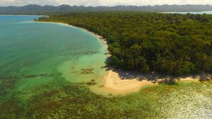 An aerial view of a tropical beach with clear turquoise waters, a sandy shoreline, and dense green forest. - Lilan Nature, Modern House N°1 with private swimming pool, Tennis and Pickleball (Cahuita)