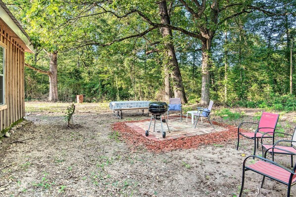 A backyard with a barbecue grill, a bench, and a small tree.