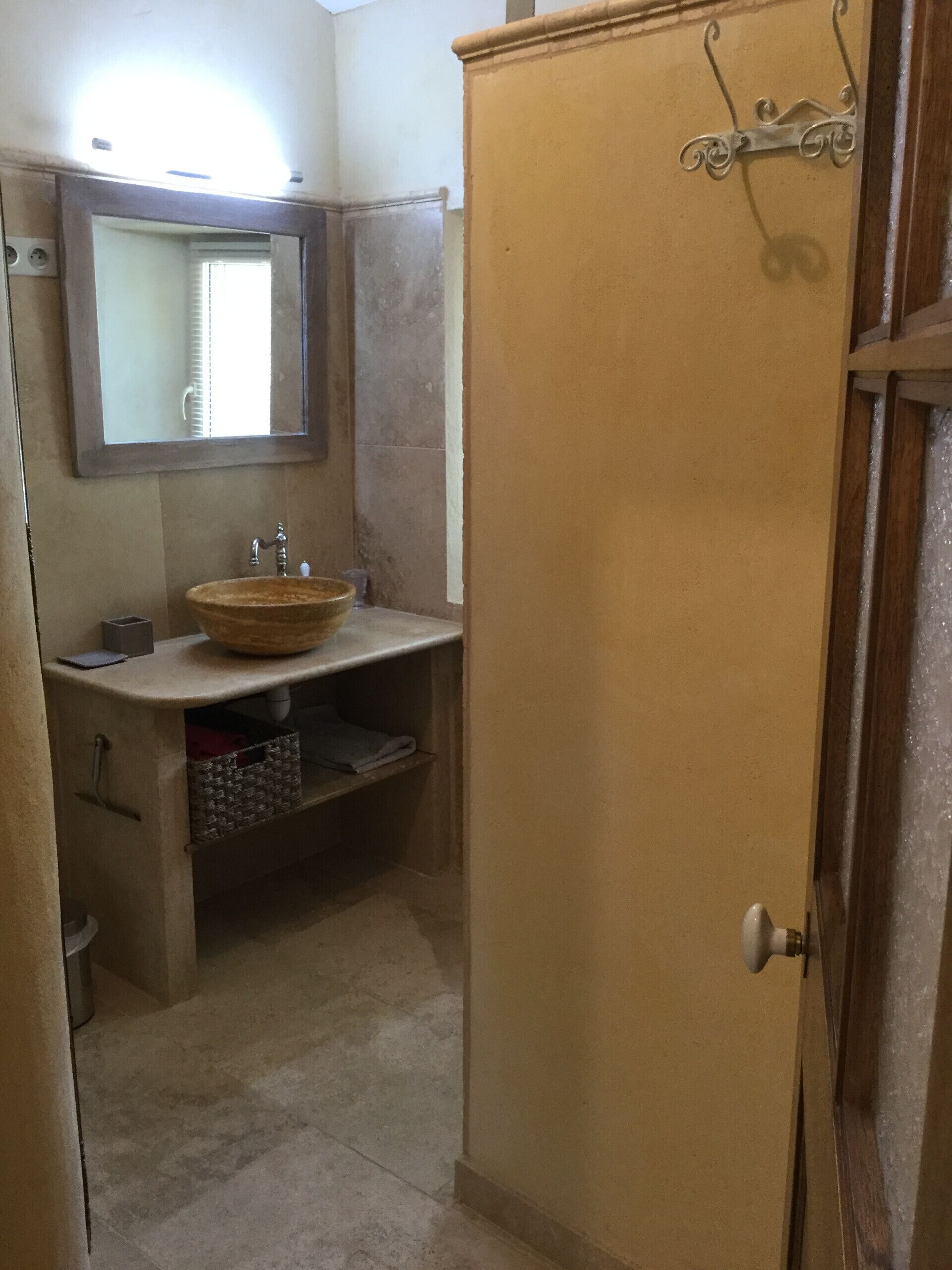 A bathroom with a large mirror, a round sink, and a cabinet with a decorative handle.