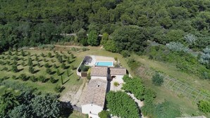 Eine Villa mit Swimmingpool, umgeben von Weinbergen und dichtem Wald, mit Bergen im Hintergrund.