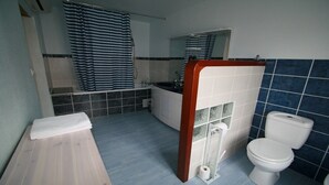 Ein Badezimmer mit Badewanne, Toilette und Duschbereich.