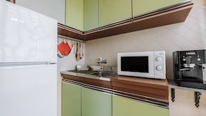 A kitchen with a white refrigerator, a microwave, and a coffee machine.