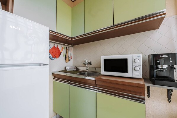 Una cocina con un refrigerador blanco, un microondas y una cafetera.