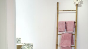 A bathroom with a wooden ladder, pink towels, a white sink, and a patterned rug. - Studio, garden, jacuzzi, sauna, yoga, massages (Soorts-Hossegor)
