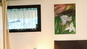 A bedroom with a bed, a bedside lamp, a window with a curtain, and a painting on the wall. - Studio, garden, jacuzzi, sauna, yoga, massages (Soorts-Hossegor)