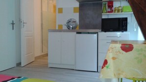 Une cuisine compacte avec des meubles blancs, un four à micro-ondes et une petite cuisinière.