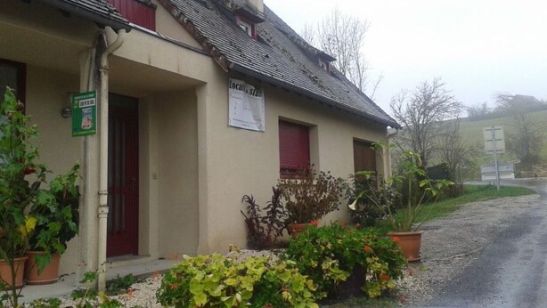 Un bâtiment avec une enseigne, une porte rouge et des plantes en pot.
