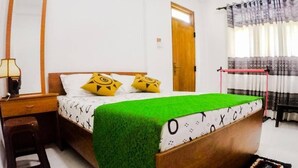 A bedroom with a bed, a desk, a chair, and a window with curtains. - Sunwon Holiday Home (Dambulla)