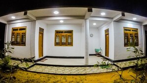 A circular building with white walls and wooden-framed windows, featuring a central door and multiple entry points. - Sunwon Holiday Home (Dambulla)