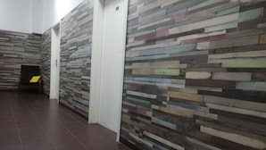 A hallway with a modern, multicolored wooden wall design and a tiled floor. - Lorf Hostel&Coffee (Stare Miasto)