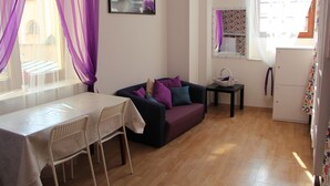 A room with a sofa, a dining table, and a refrigerator. - Lorf Hostel&Coffee (Stare Miasto)