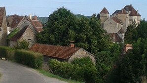 A rural village with stone buildings, a road, and a castle in the background. - ----- Green Studio ----- (Curemonte)