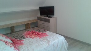 A bedroom with a bed, a wooden bench, a dresser, and a television on top. - ----- Green Studio ----- (Curemonte)