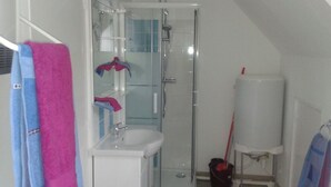 A small bathroom with a glass shower enclosure, a white sink, and a mirror. - ----- Green Studio ----- (Curemonte)